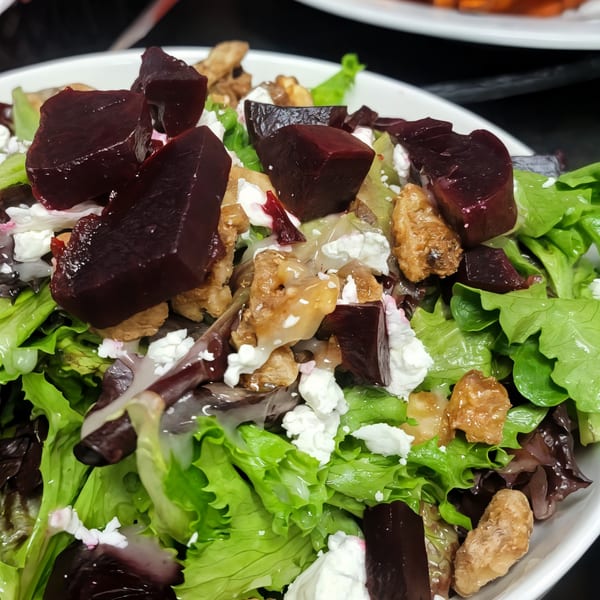 Close-up of a vibrant salad with green and red lettuce, beets, walnuts, and feta cheese.